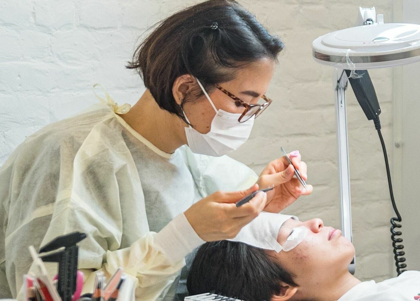Technician applies eyelash extensions at Lash-bar Foula, New York, New York, US, ensuring precision and quality.
