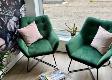 Cozy seating area with green chairs at Belle Amour, Bagshot, England, GB, featuring floral wallpaper and soft lighting.