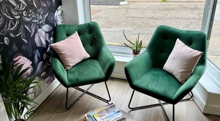 Cozy seating area with green chairs at Belle Amour, Bagshot, England, GB, featuring floral wallpaper and soft lighting.