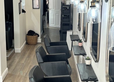 Elegant interior of Belle Amour salon, Bagshot, England with black chairs and mirrored stations.