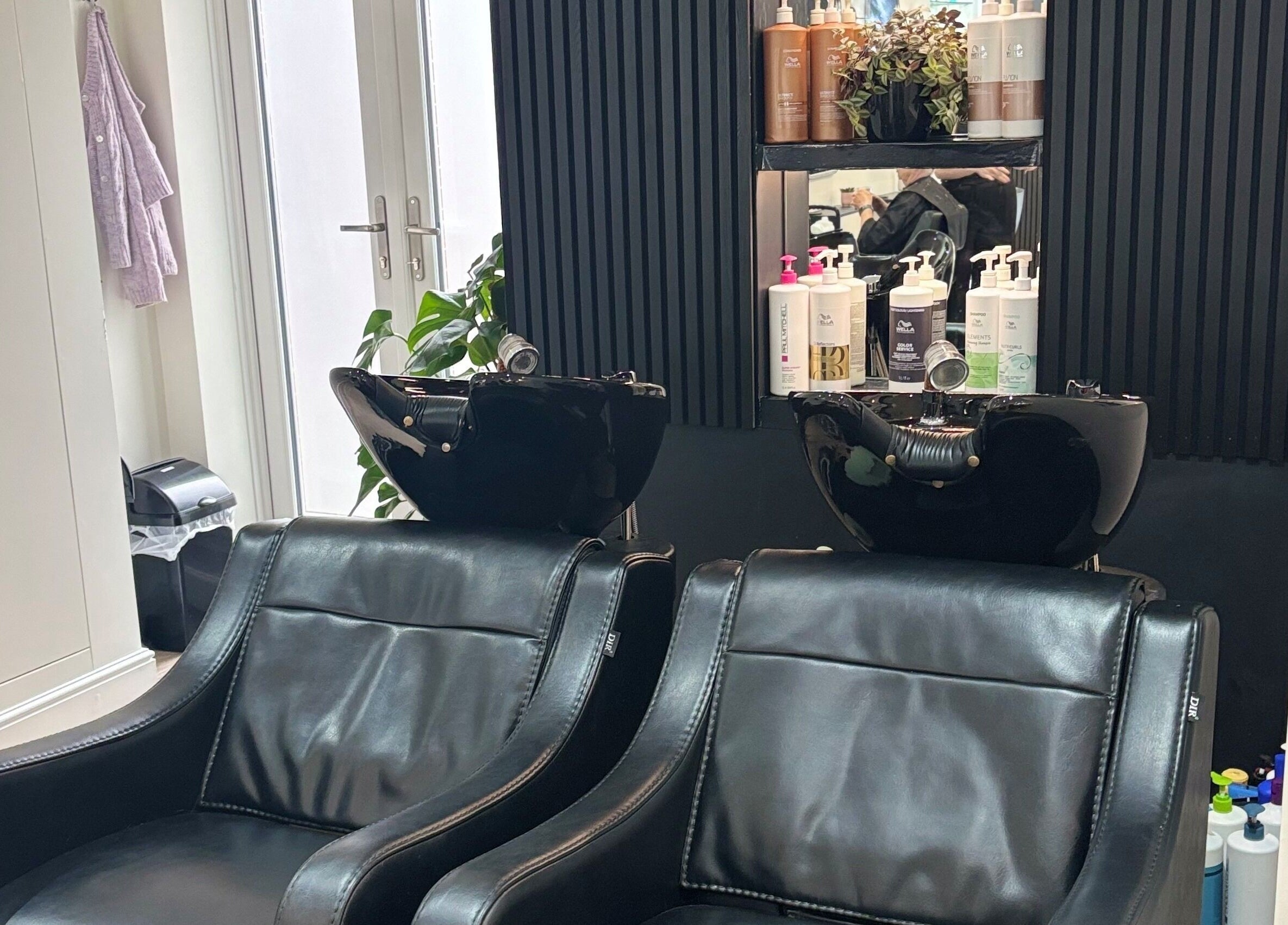 Elegant salon wash area at Belle Amour, Bagshot, England, GB, featuring plush black leather chairs.
