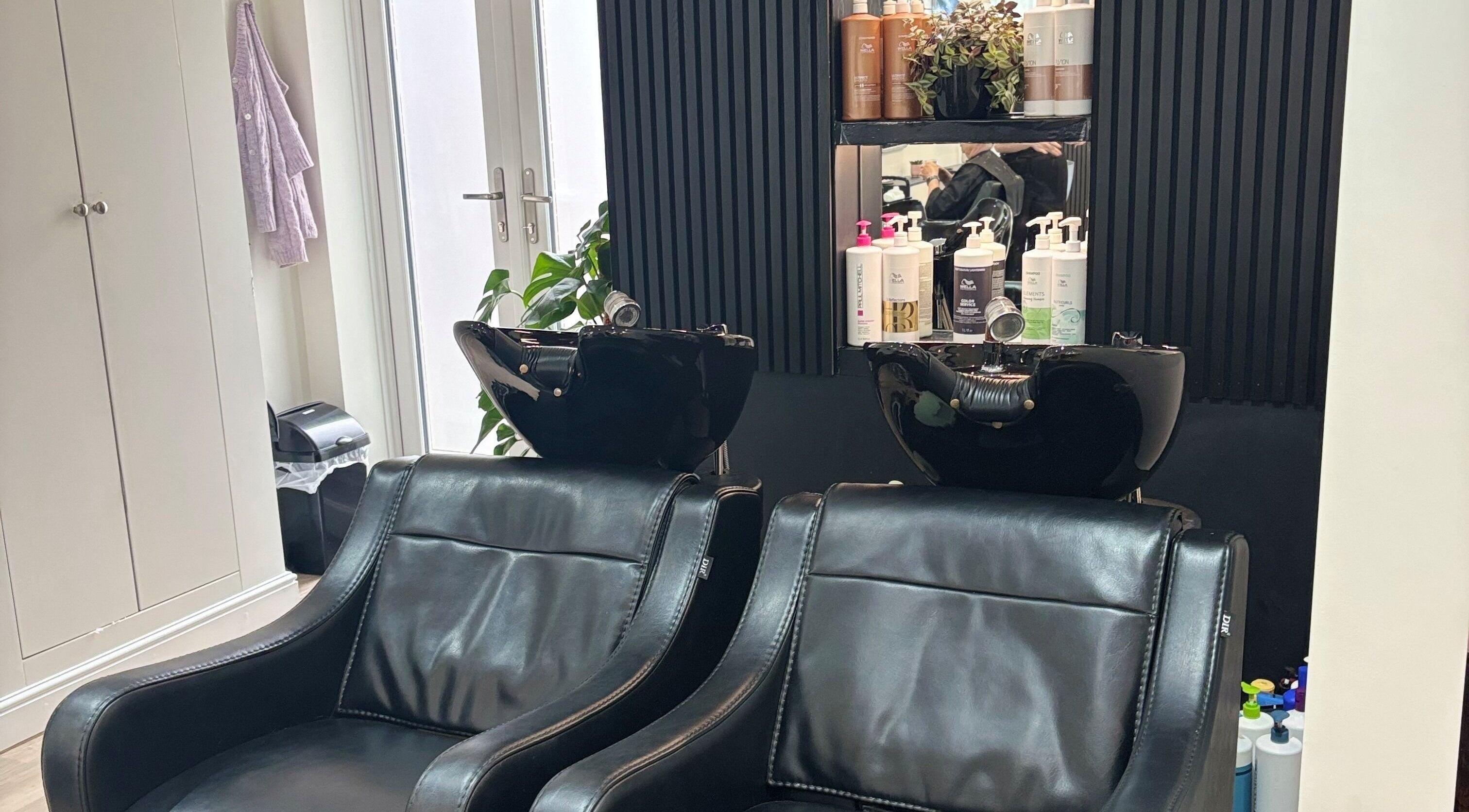 Elegant salon wash area at Belle Amour, Bagshot, England, GB, featuring plush black leather chairs.