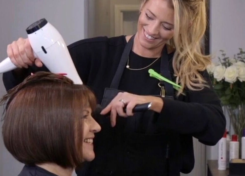 Stylist at Belle Amour in Bagshot, England, GB, expertly blow-drying a client's hair.
