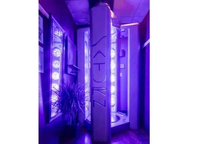 Modern tanning booth at After Glow Tanning & Beauty - North Providence, Rhode Island, US with neon lights.