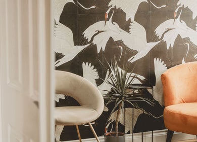 Stylish seating area at Lilys in Diss, England, GB with vibrant crane wallpaper and chic chairs.