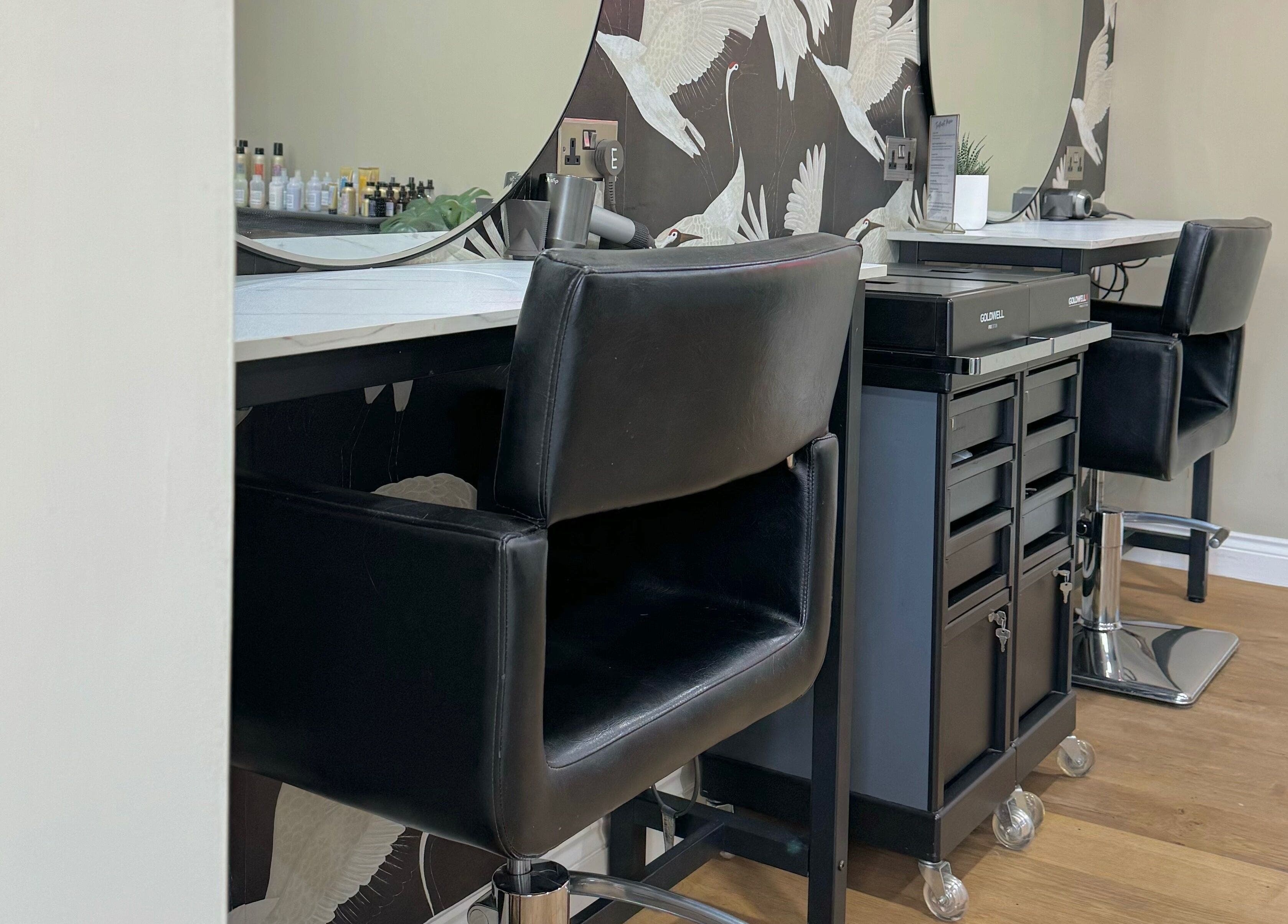 Modern salon station at Lilys in Diss, England, GB with black chairs and elegant decor.