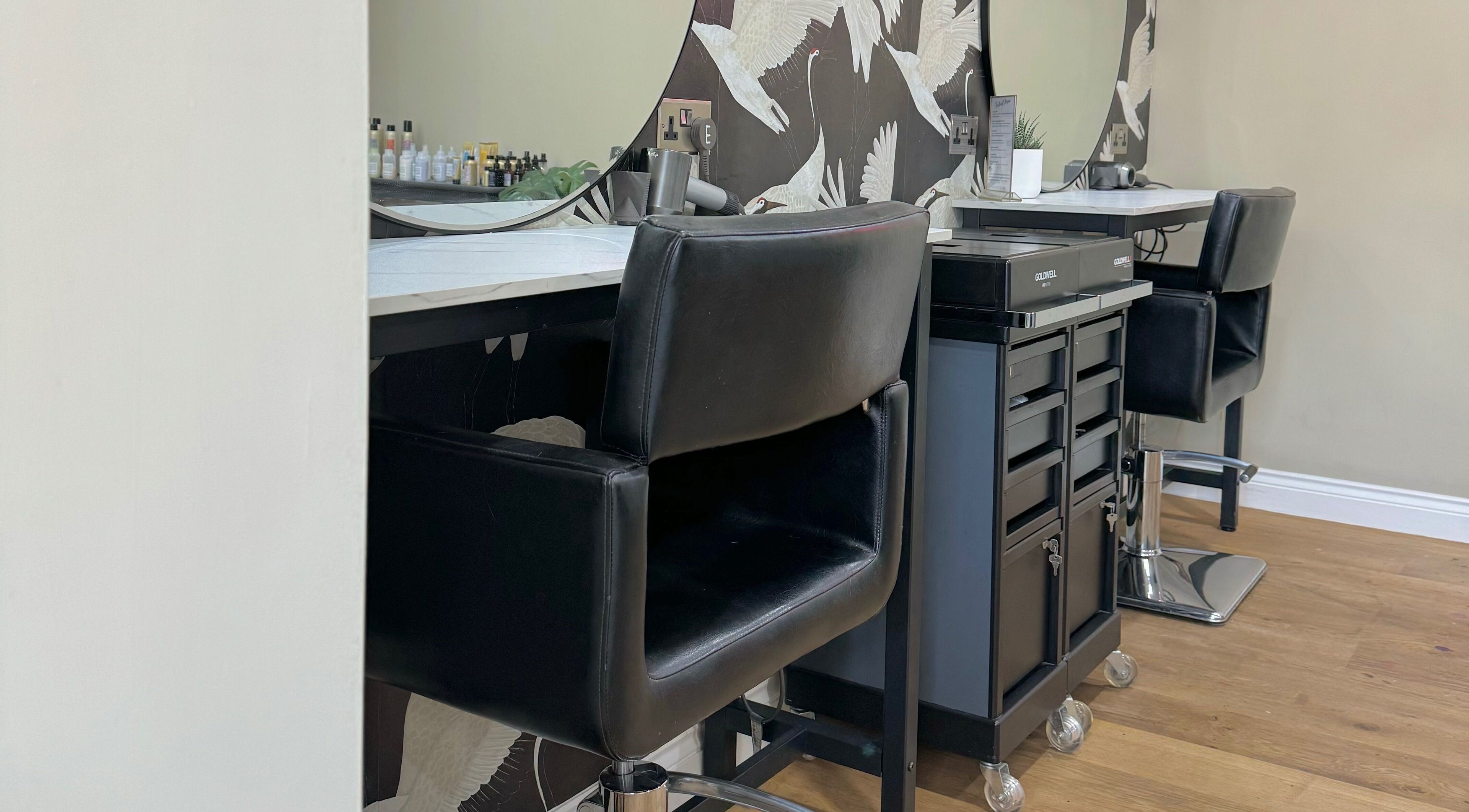 Modern salon station at Lilys in Diss, England, GB with black chairs and elegant decor.