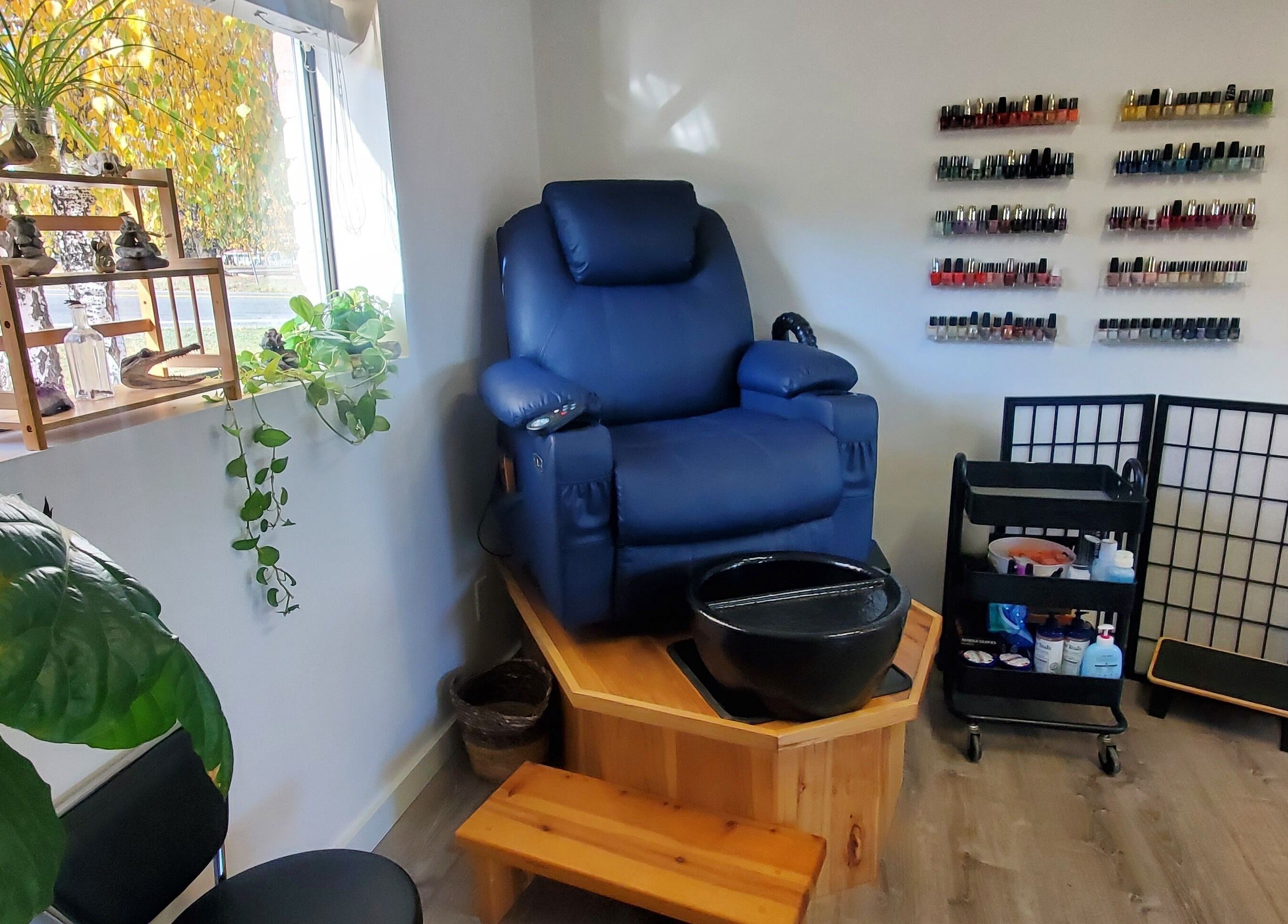 Elegant pedicure chair at Royal Digits, Etna, California, US, surrounded by nail polish selection and plants.