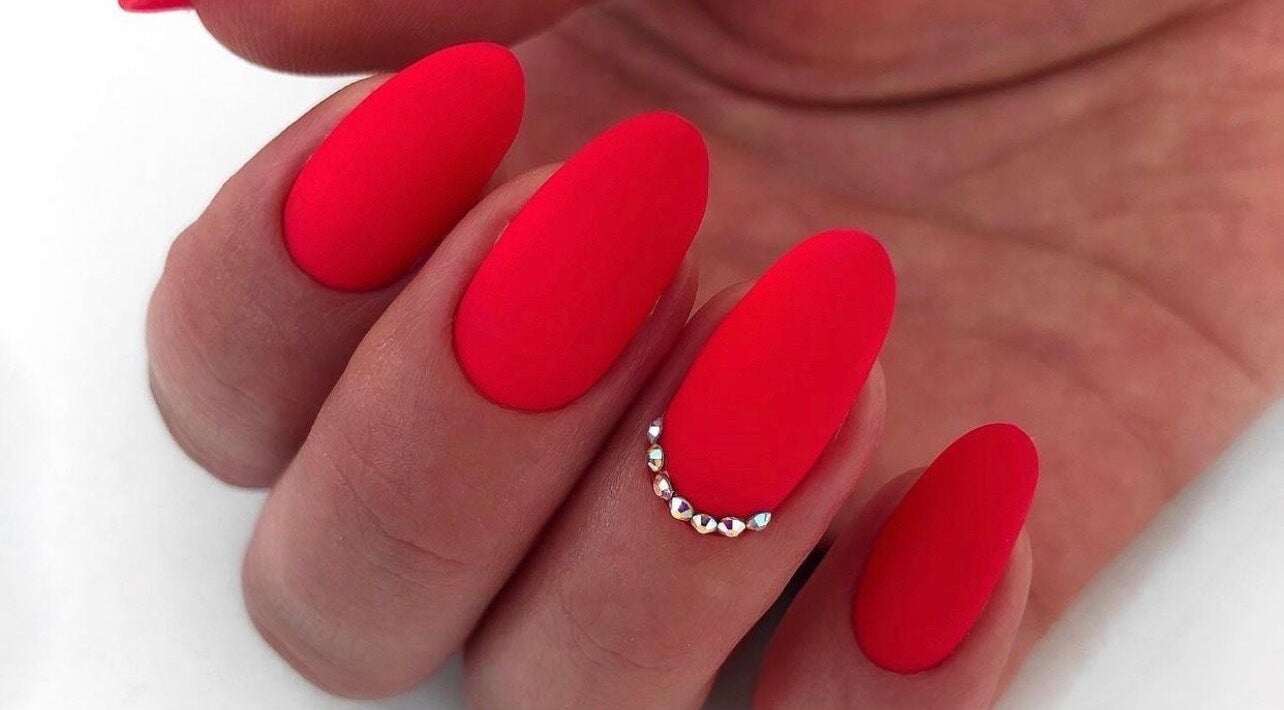 Stunning red manicure with gem accents at Nail Art Studio, Gainsborough, England, GB.