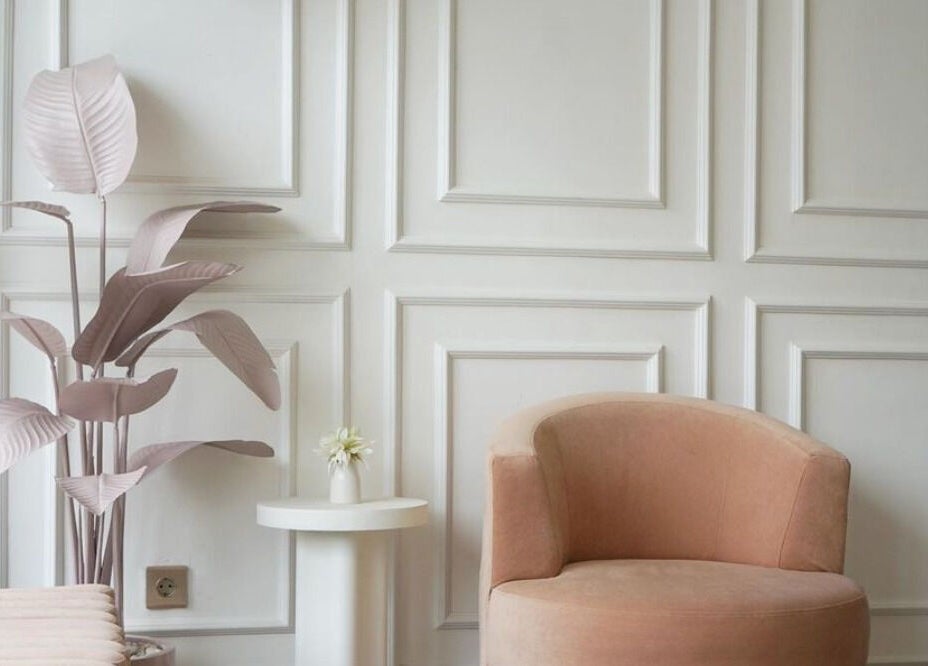 Noona Glam lounge with pink chair, white panel wall, and plant. Located in Bali, Bali, ID.