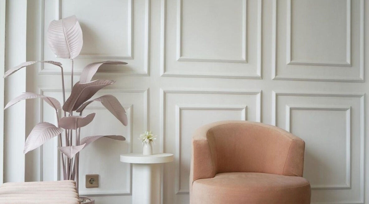Noona Glam lounge with pink chair, white panel wall, and plant. Located in Bali, Bali, ID.
