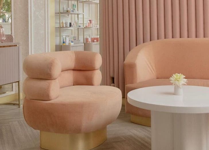 Stylish interior of Noona Glam in Bali, Bali, ID, with peach chairs and vase on a sleek white table.