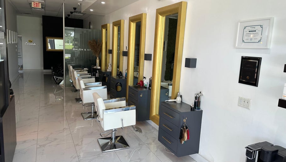 Interior of Leonardo Trigueros Salon & Spa in Fort Lauderdale, Florida, US with chic white chairs and golden mirrors.