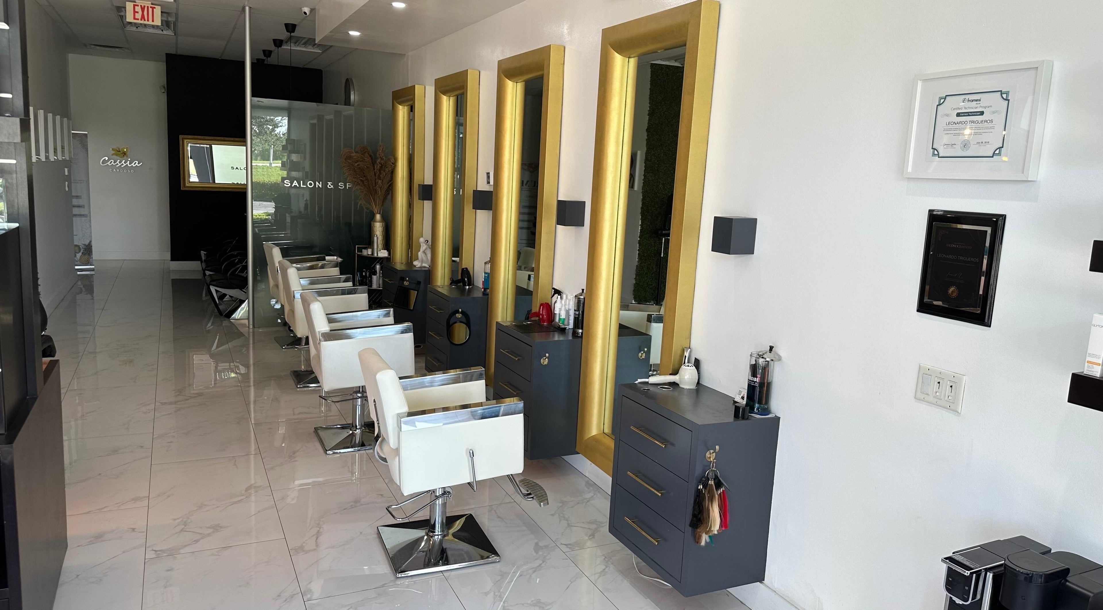 Interior of Leonardo Trigueros Salon & Spa in Fort Lauderdale, Florida, US with chic white chairs and golden mirrors.