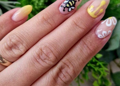 Bee-themed nail art at Dragonfly Beauty, South Hiendley, England, GB with greenery in the background.