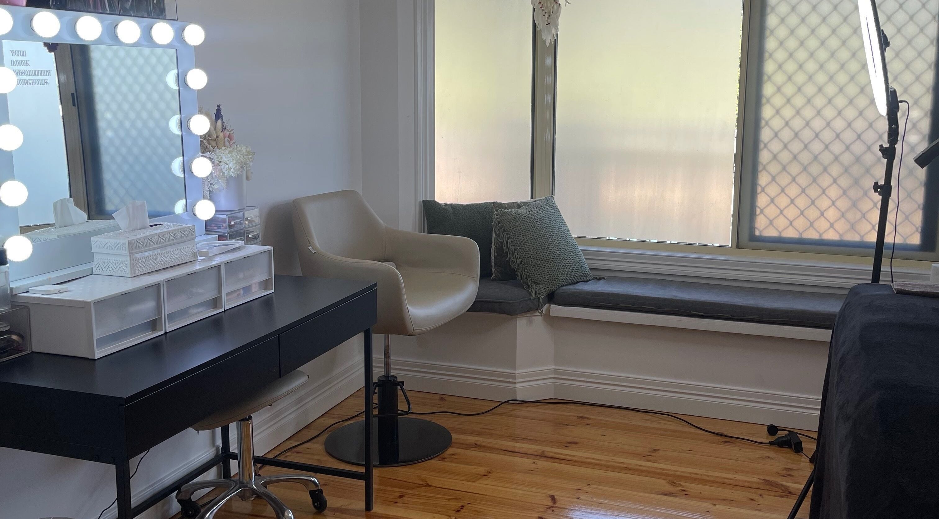 Cozy makeup station at Wild House of Beauty, Lowood, Queensland, AU with a lit mirror and seating.