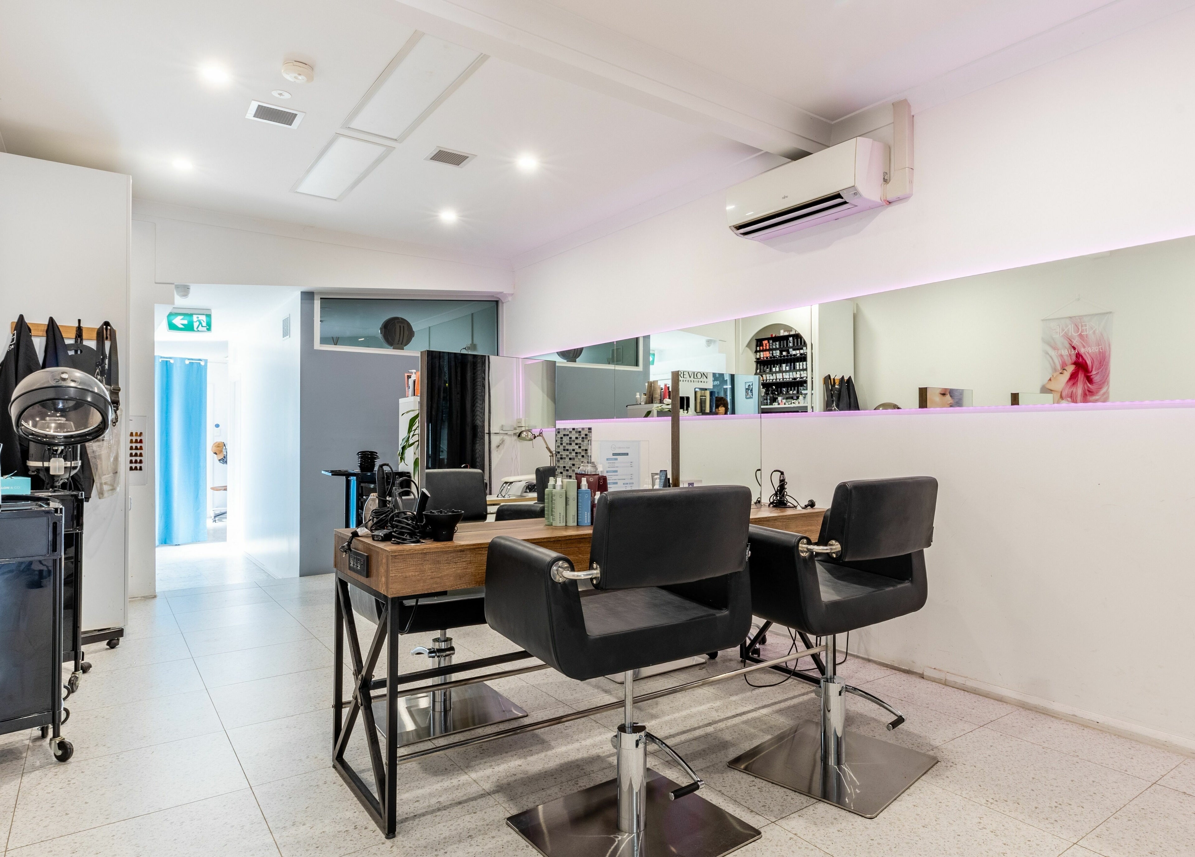 Modern salon interior at Collective Hair, Mascot, Pensioners 25% Off, AU, with stylish black chairs and mirror.
