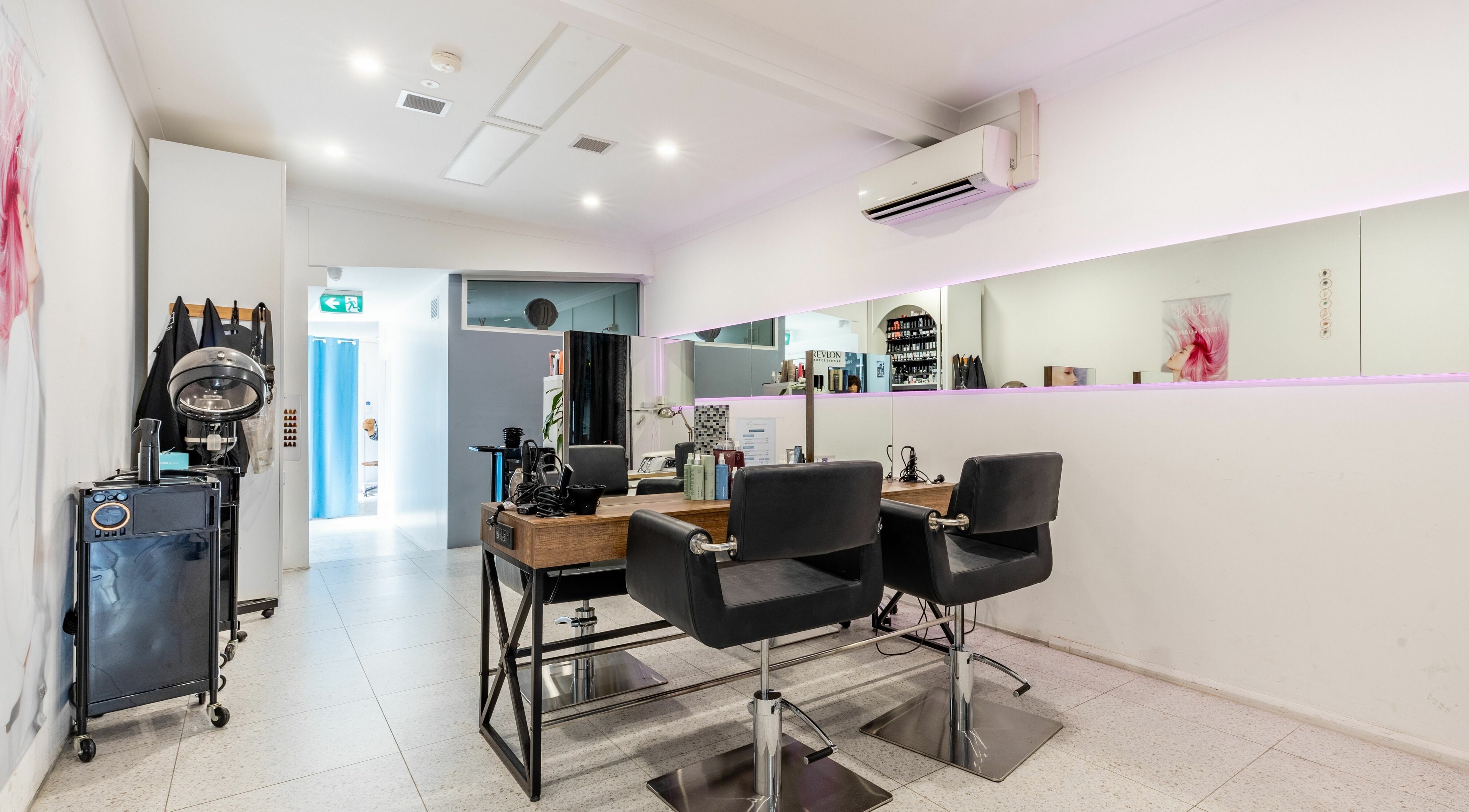 Modern salon interior at Collective Hair, Mascot, Pensioners 25% Off, AU, with stylish black chairs and mirror.