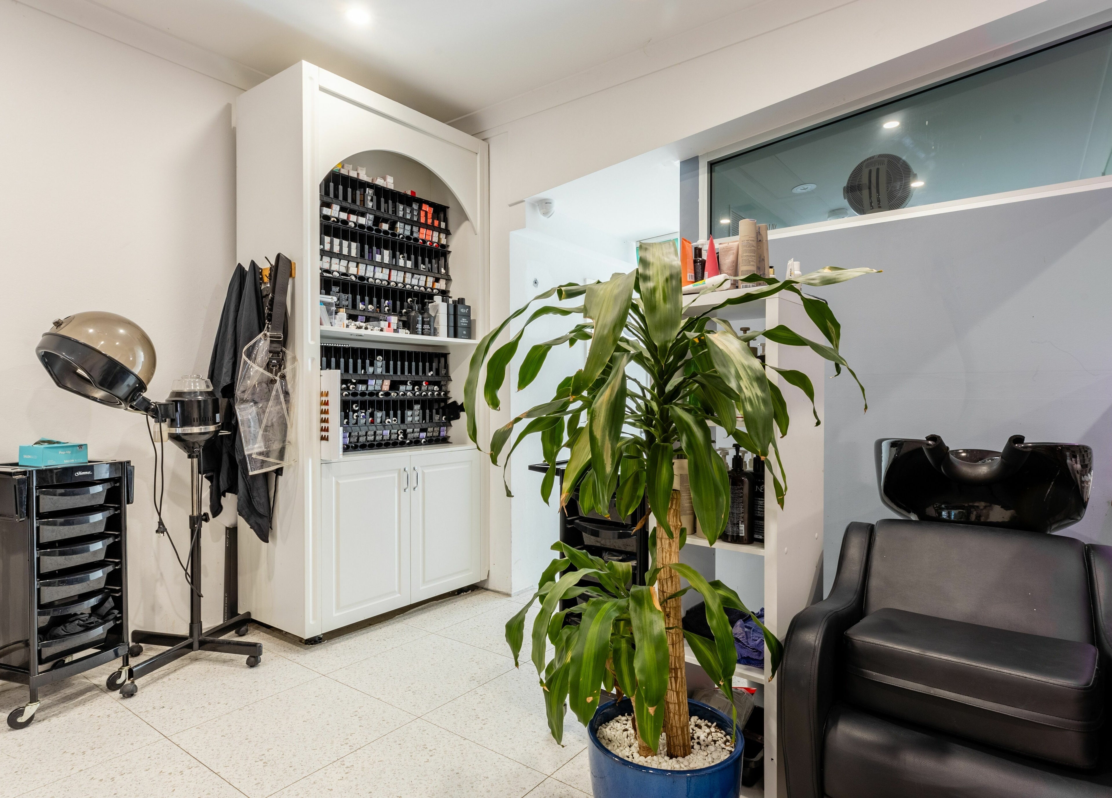 Relaxed salon corner at Collective Hair, Mascot, Pensioners 25% Off, AU. Features styling tools and plant.