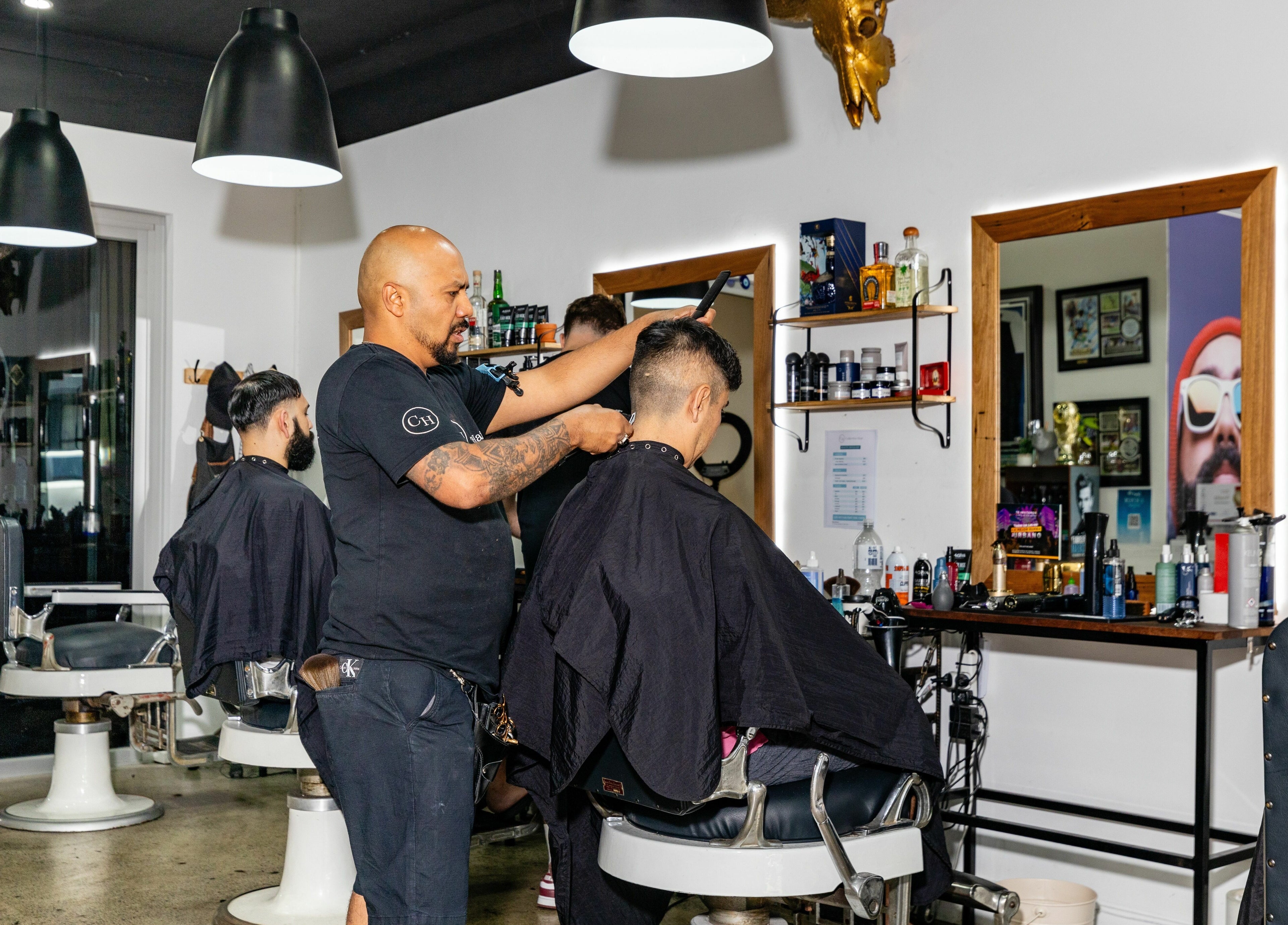 Barber at Collective Hair in Mascot giving a stylish haircut, featuring modern salon interior, Pensioners 25% Off.