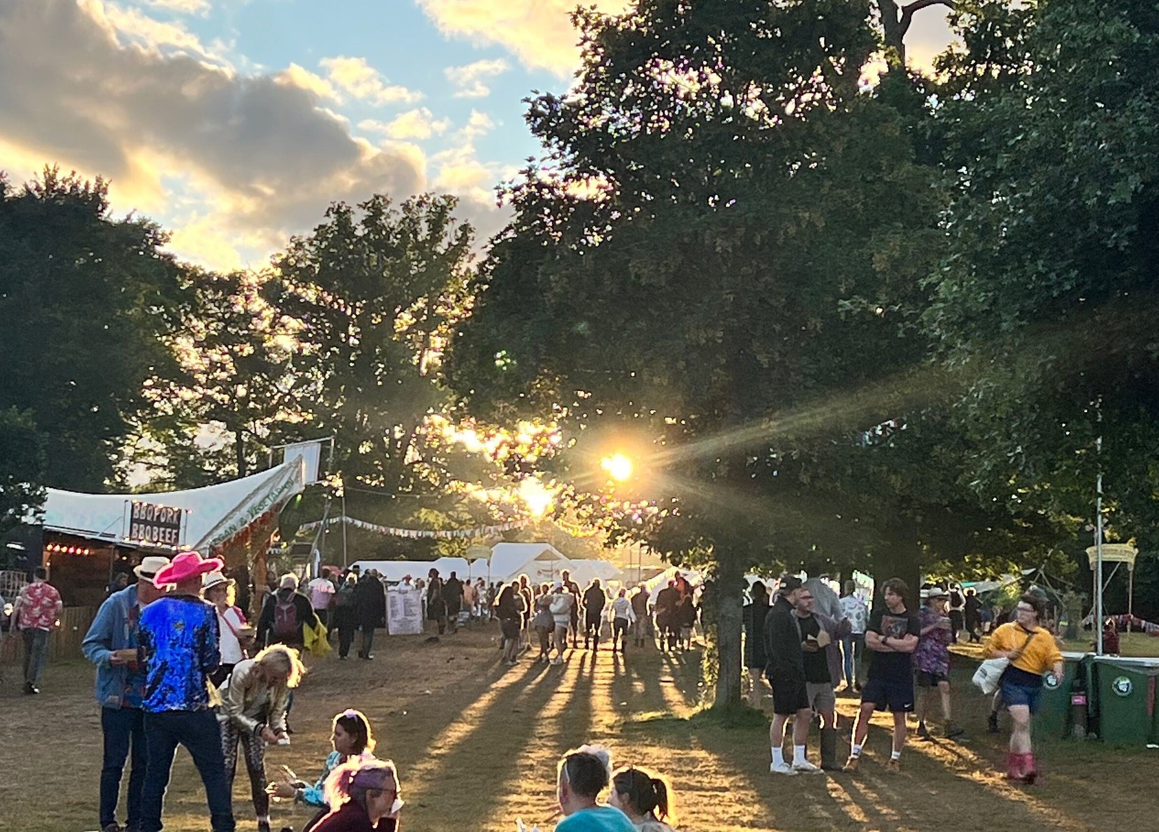 A vibrant outdoor event at Latitude Luxury, Southwold, England, GB with people enjoying the sunset.