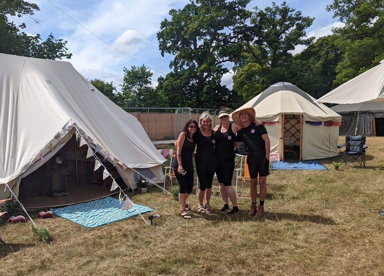 Guests enjoying glamping tents at Latitude Luxury, Southwold, England, GB amidst lush greenery.
