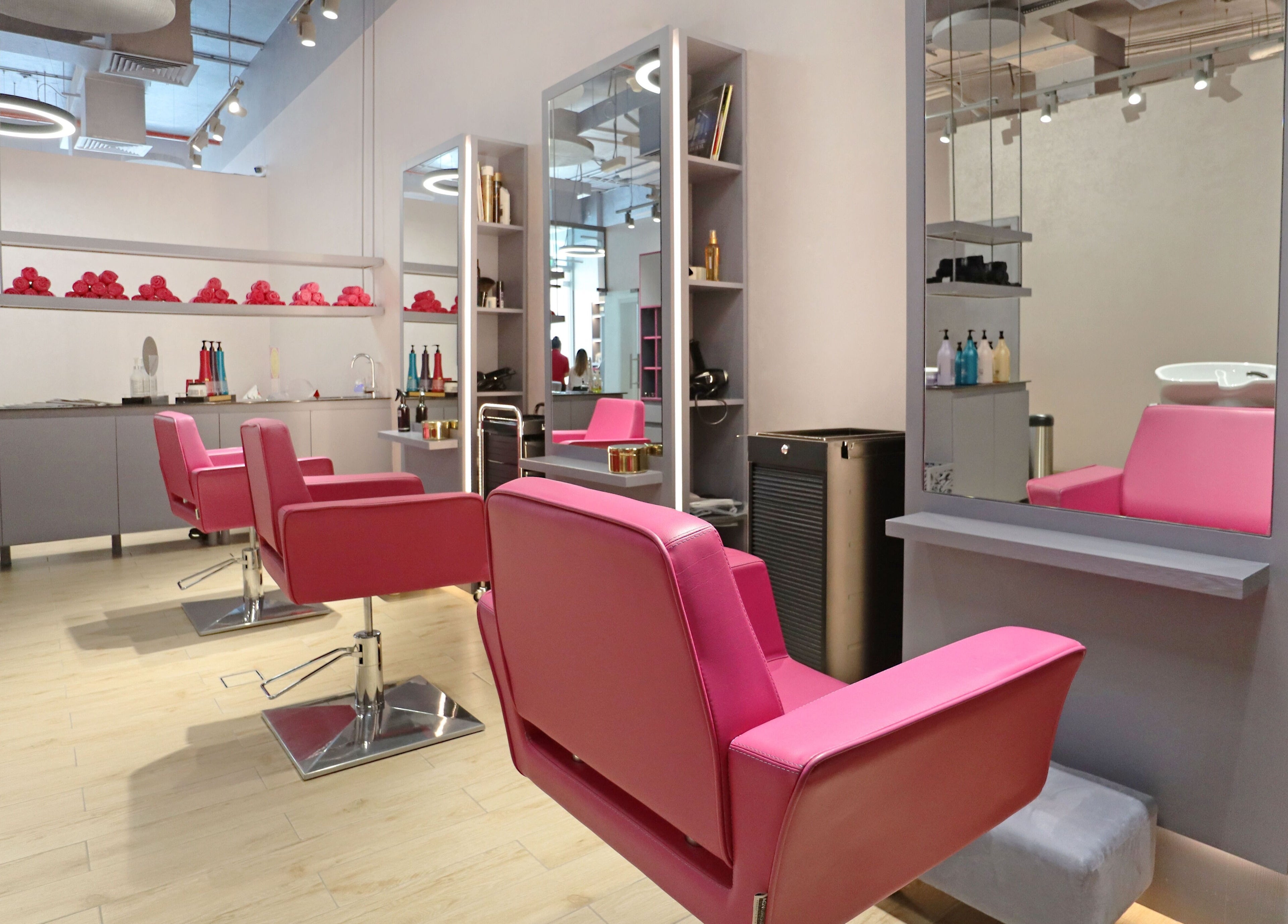 Modern chic salon interior at Mastercuts UAE, Dubai, Dubai, AE with vibrant pink chairs and sleek stations.