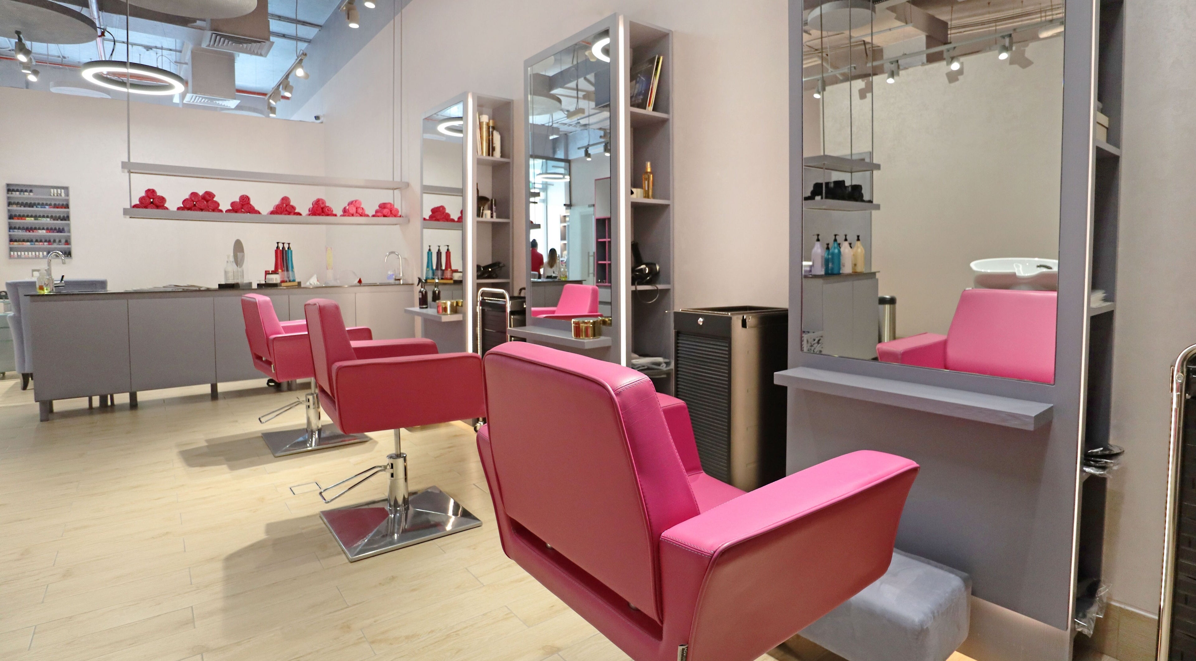 Modern chic salon interior at Mastercuts UAE, Dubai, Dubai, AE with vibrant pink chairs and sleek stations.