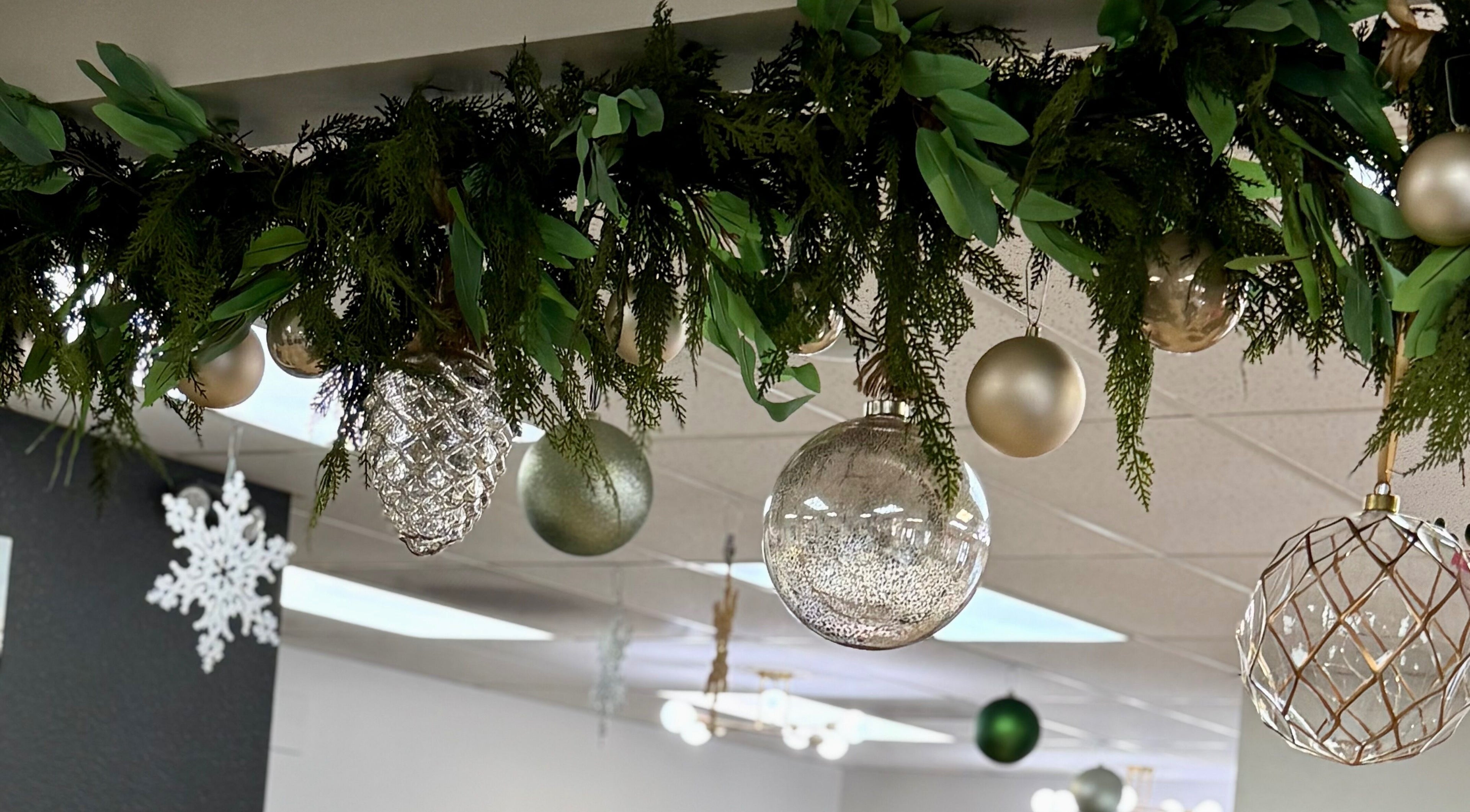 Festive ceiling decor at Katie at Salon Nuvo in Lee's Summit, Missouri, US with green foliage and ornaments.