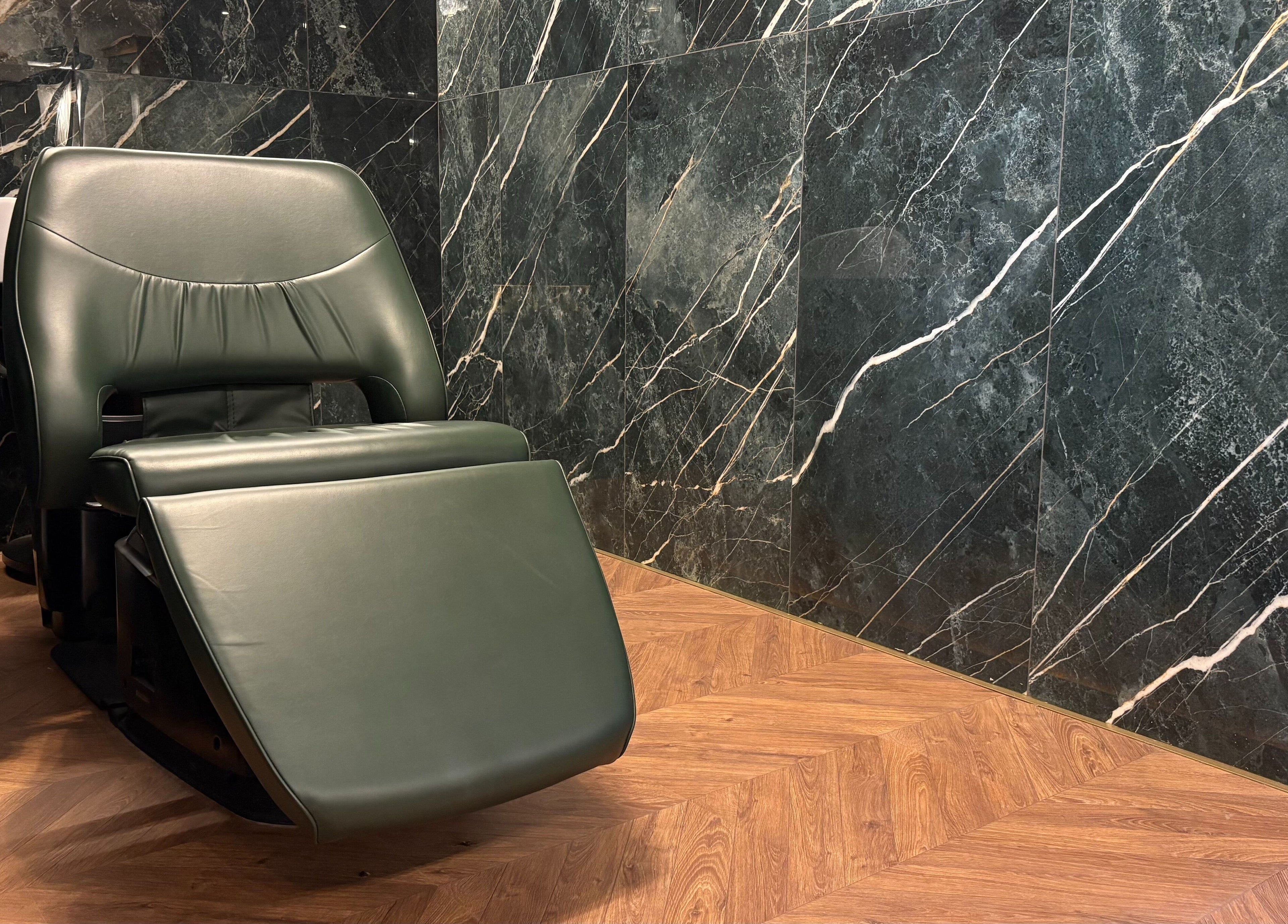 Green reclining chair in Rodeo Drive Beauty, Limassol, Lemesos, CY, with marble walls and wooden floor.