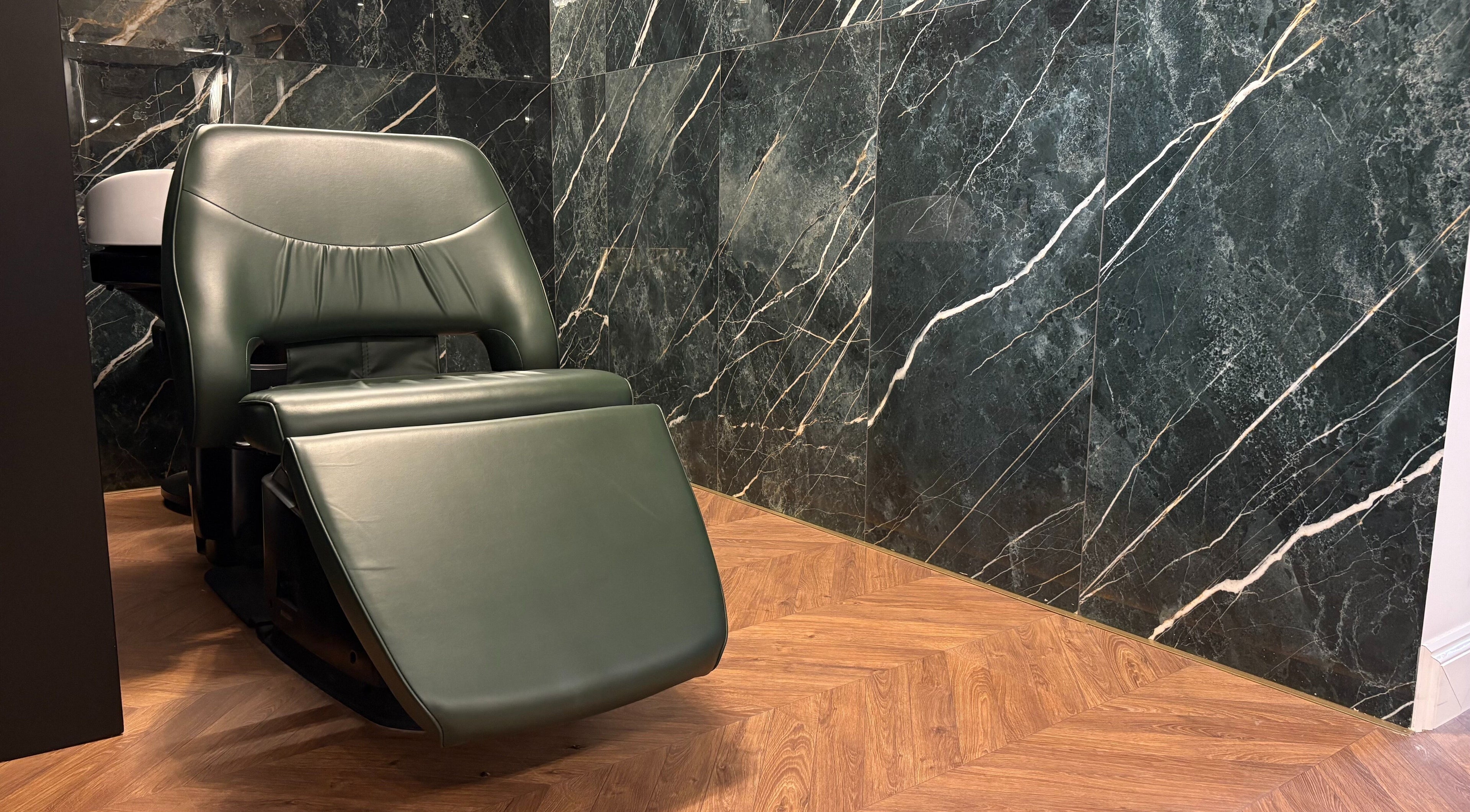 Green reclining chair in Rodeo Drive Beauty, Limassol, Lemesos, CY, with marble walls and wooden floor.