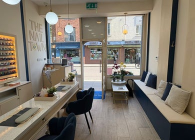 Elegant interior of The Nail Town in London, England, GB with plush seating and vibrant nail polish display.
