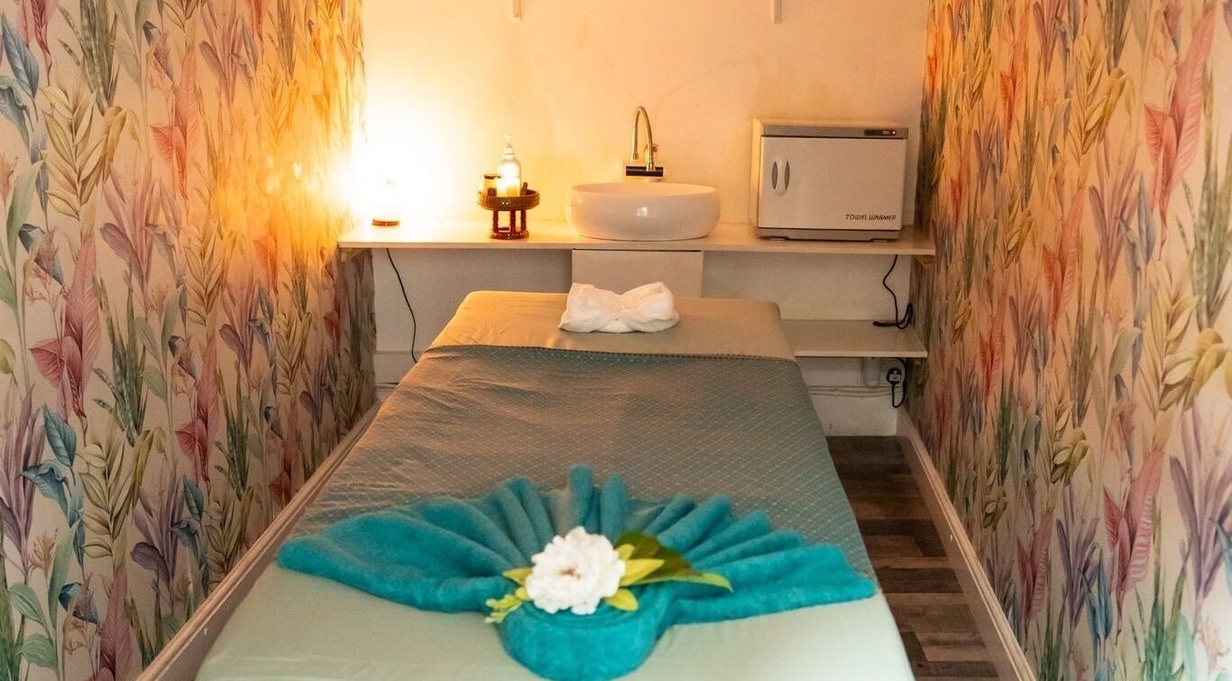 Tranquil massage room at Gold Star Thai Massage, London, England, GB with floral wallpaper and ambient lighting.
