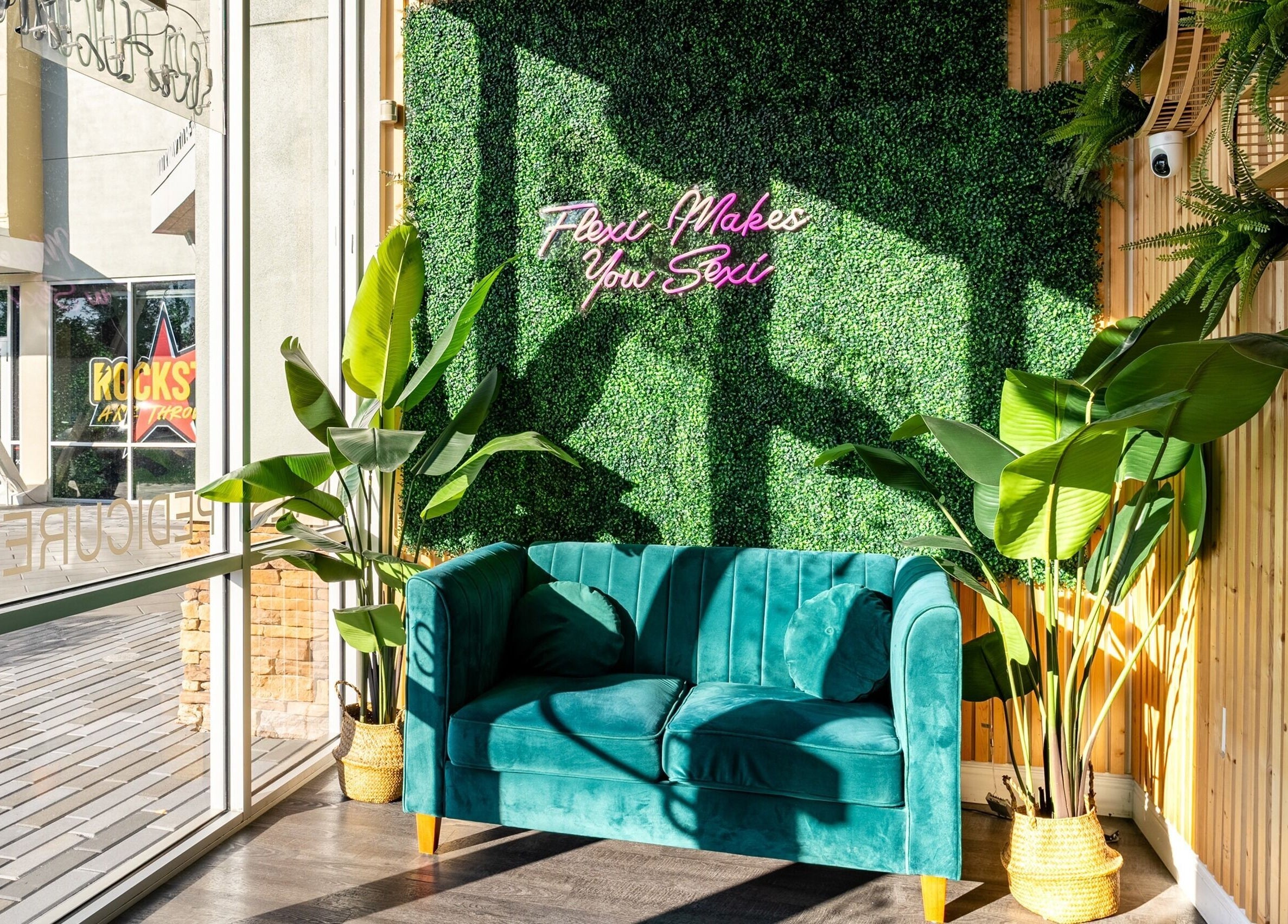 Cozy seating area at Flex-I Nails Spa in Orlando, Florida, US, featuring vibrant plants and plush green sofa.