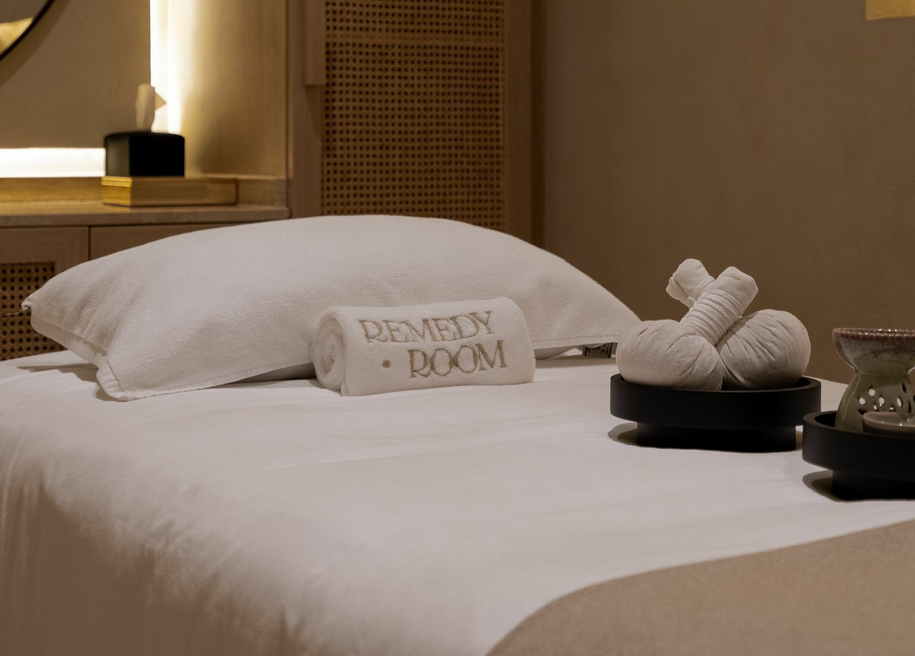 A serene spa bed setup with plush towels and herbs at Remedy Room, Abu Dhabi, AE.