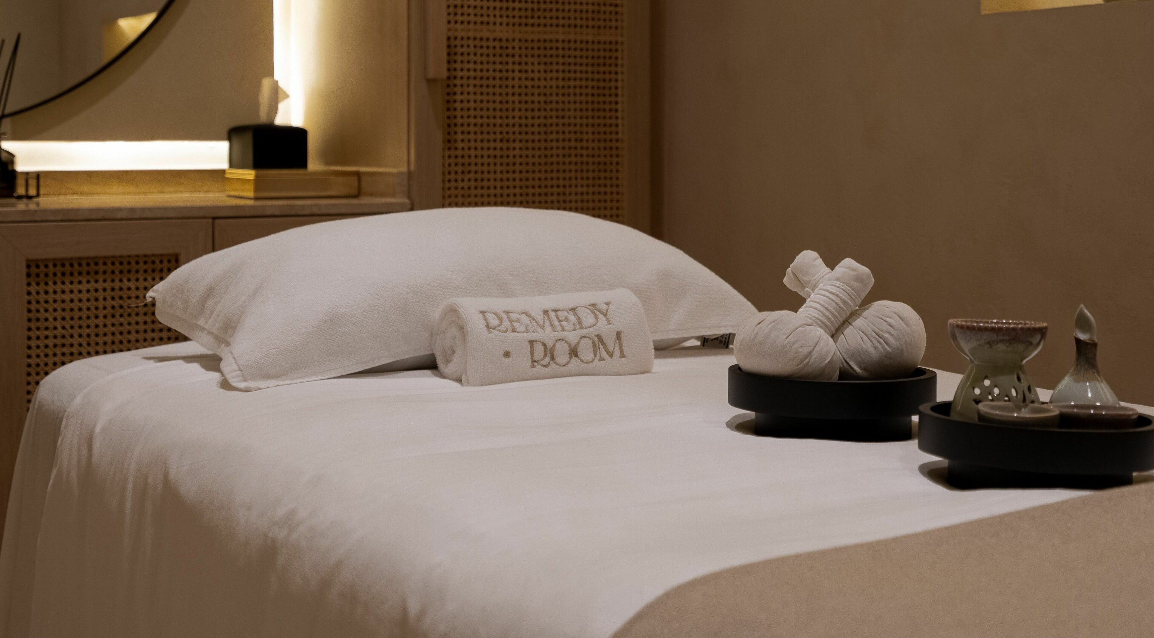 A serene spa bed setup with plush towels and herbs at Remedy Room, Abu Dhabi, AE.