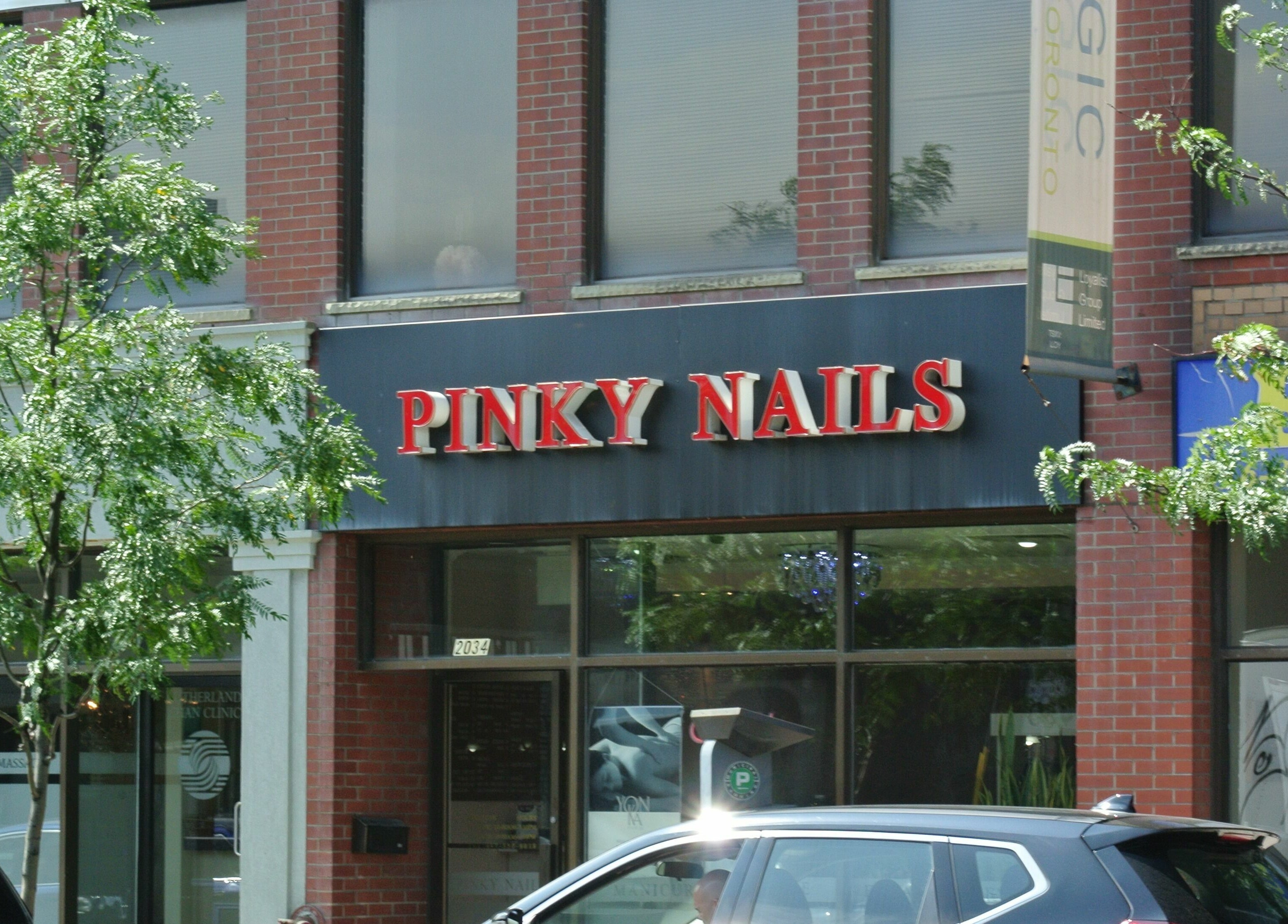 Entrance to Pinky Nails and Spa on Davisville, showcasing red signage in Toronto, Ontario, CA.