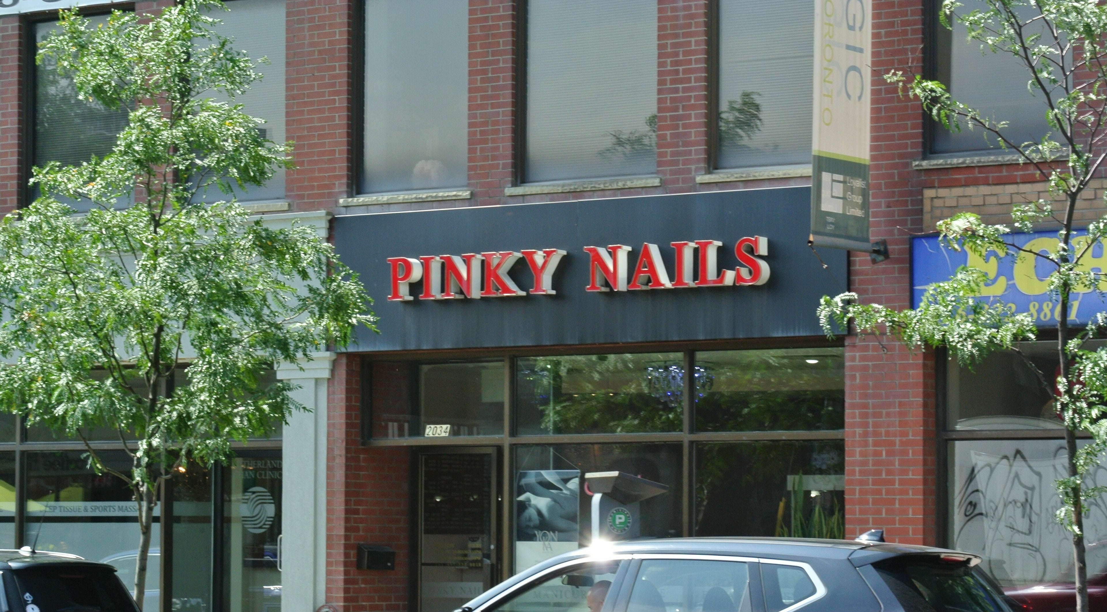 Entrance to Pinky Nails and Spa on Davisville, showcasing red signage in Toronto, Ontario, CA.