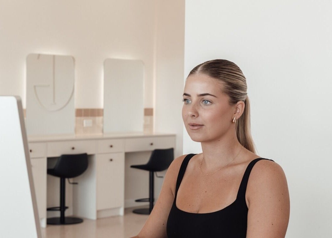 Professional woman at Glam Theory Studios, Heathmont, Victoria, AU, sitting elegantly at a modern desk.