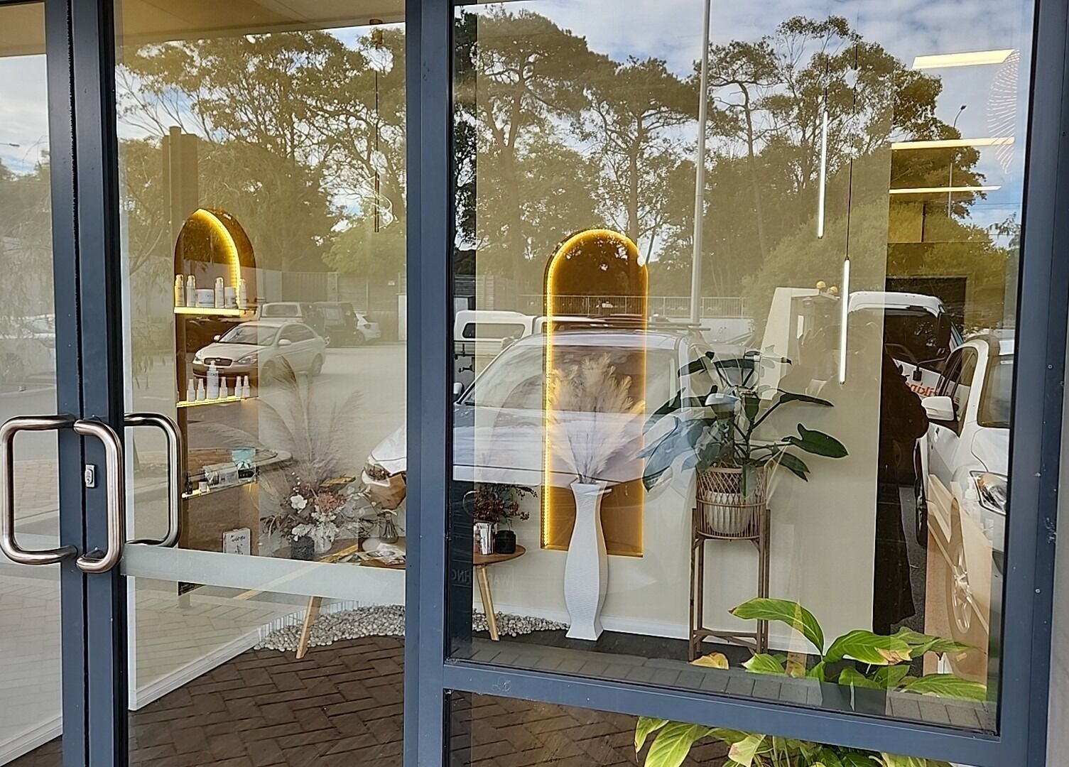 Front glass door of Chee Chee Salon in Bayonet Head, Western Australia, AU showcasing interior decor reflection.