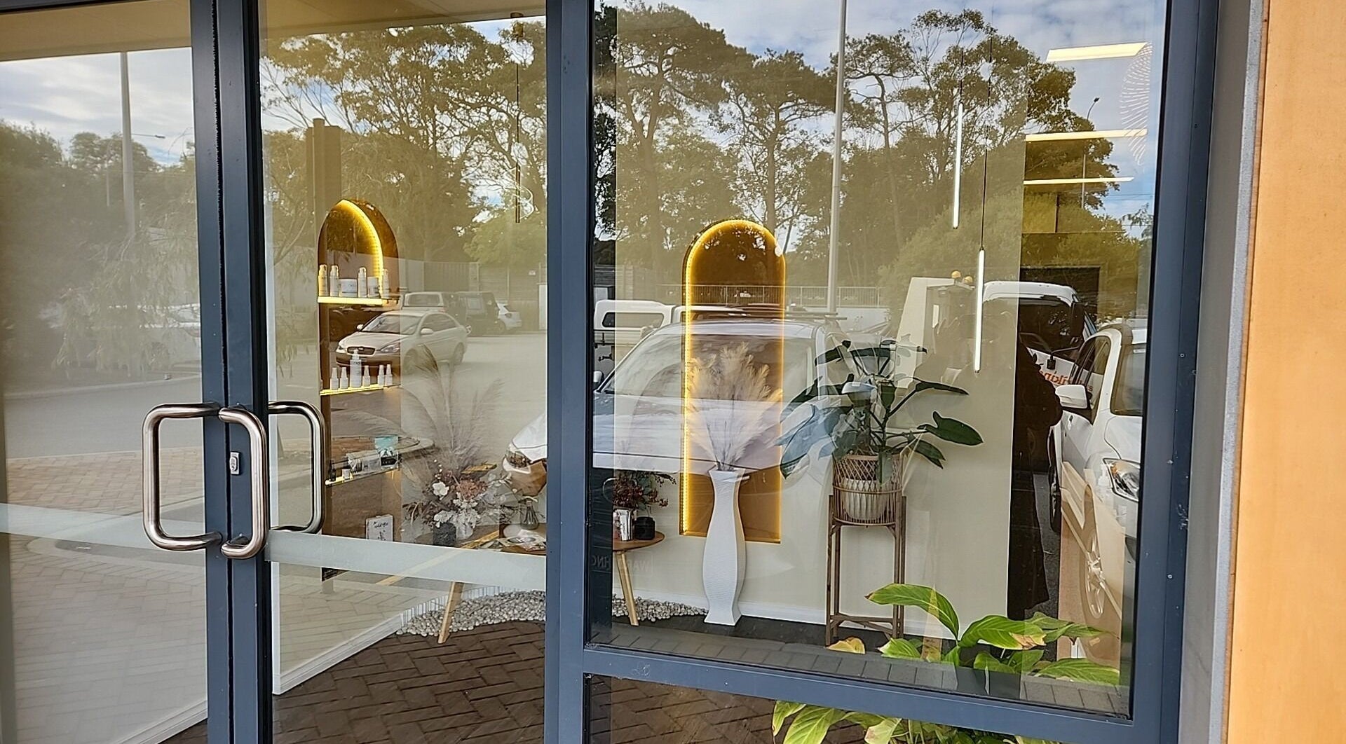 Front glass door of Chee Chee Salon in Bayonet Head, Western Australia, AU showcasing interior decor reflection.