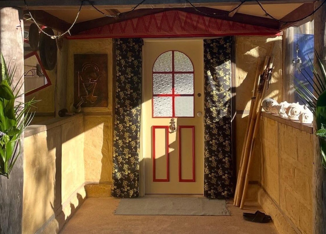 Ornate front door of Cosmic Rose, Newport, New South Wales, AU, framed by decorative greenery.