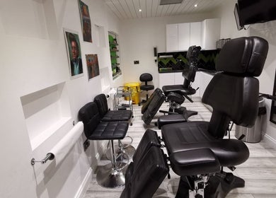 Interior of Envy Tattoo Studio, Kirkcaldy, Scotland, GB with chairs and artwork on white walls.