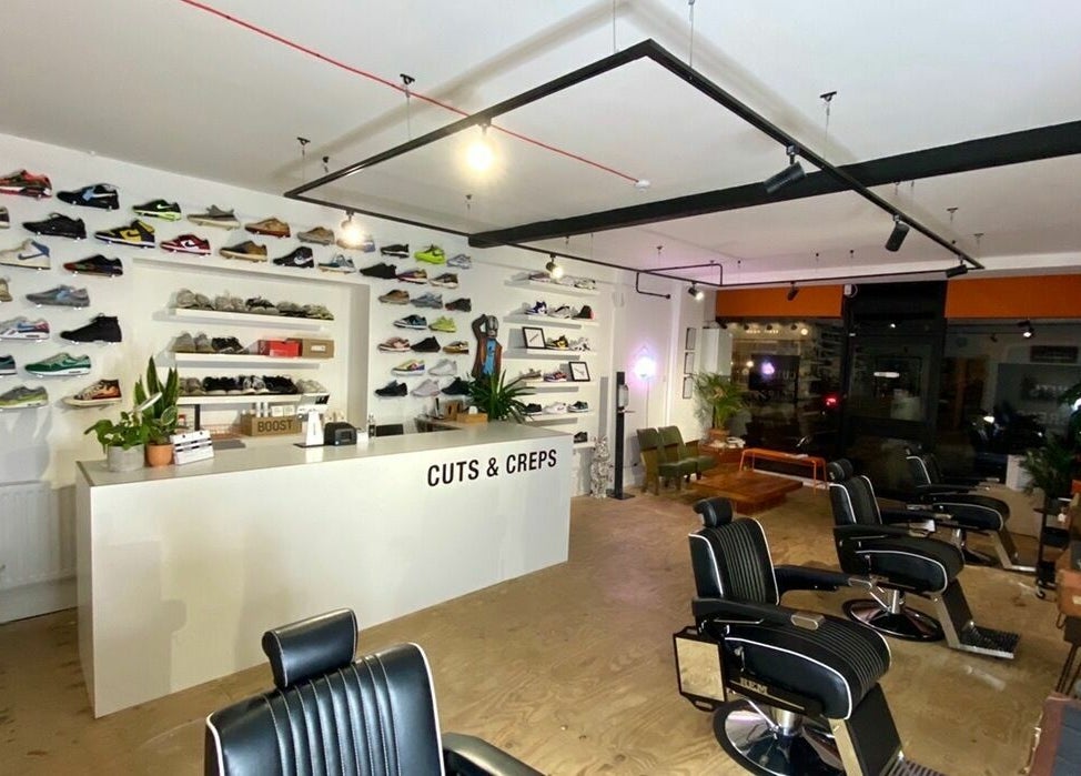 Interior of Cuts and Creps with modern barber chairs and sneaker display, Bristol, England, GB.