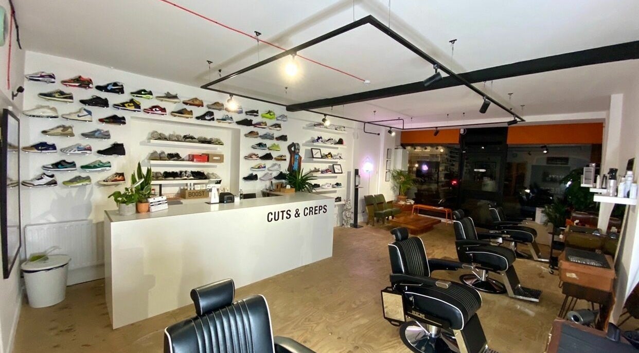 Interior of Cuts and Creps with modern barber chairs and sneaker display, Bristol, England, GB.