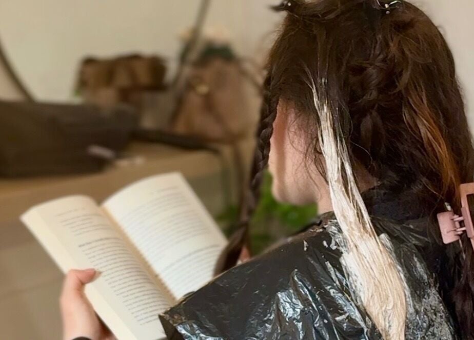 Customer enjoys reading during a hair treatment at Gabriela Leite Curly Hair Salon, Dublin, County Dublin, IE.