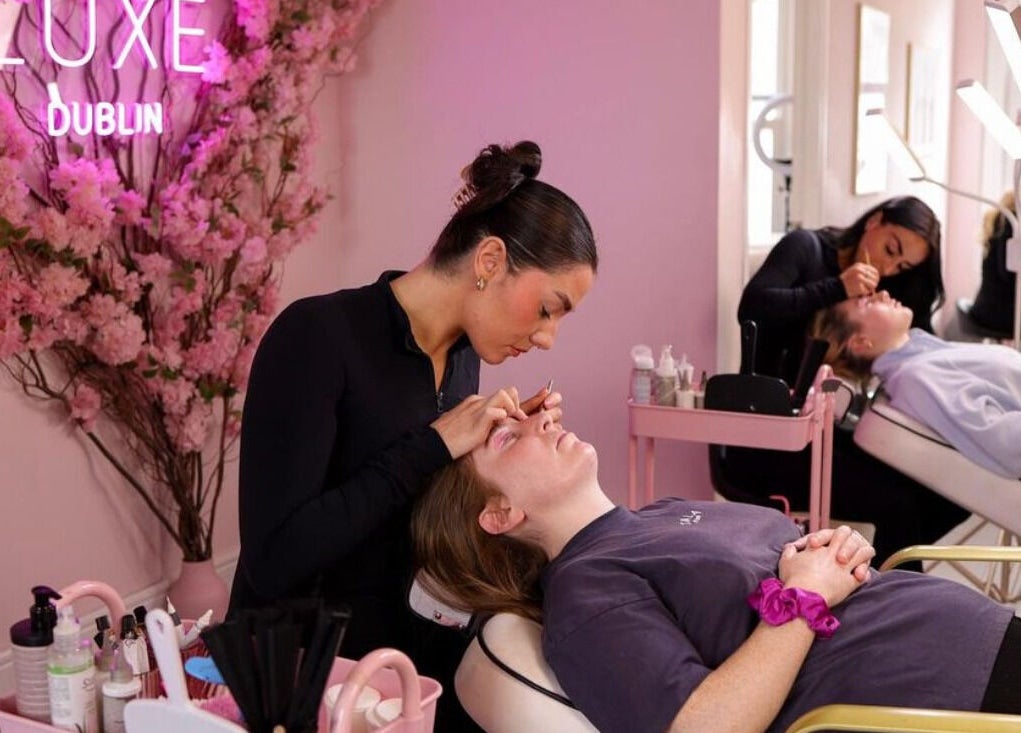 Stylist at Luxe Dublin perfecting brows in Dublin 6W, County Dublin, IE. Chic ambiance with pink decor.