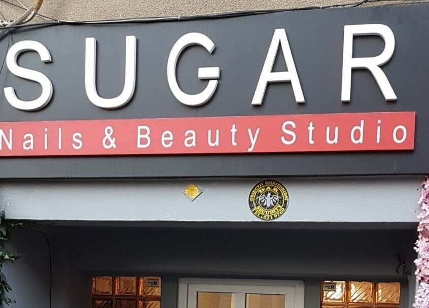 Intrarea principală a Sugar Beauty Studio în București, București, RO, decorată cu flori roz.