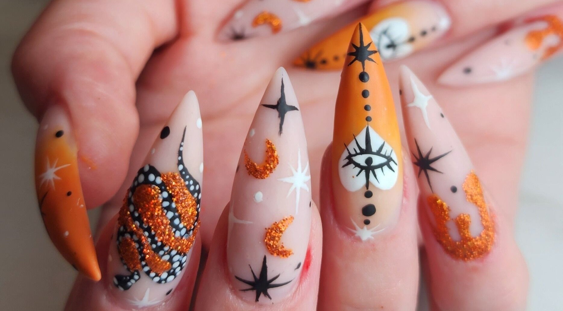 Creative nail art at Sondra's Nails and Esthetics in Lethbridge, Alberta, CA. Intricate designs with orange accents.