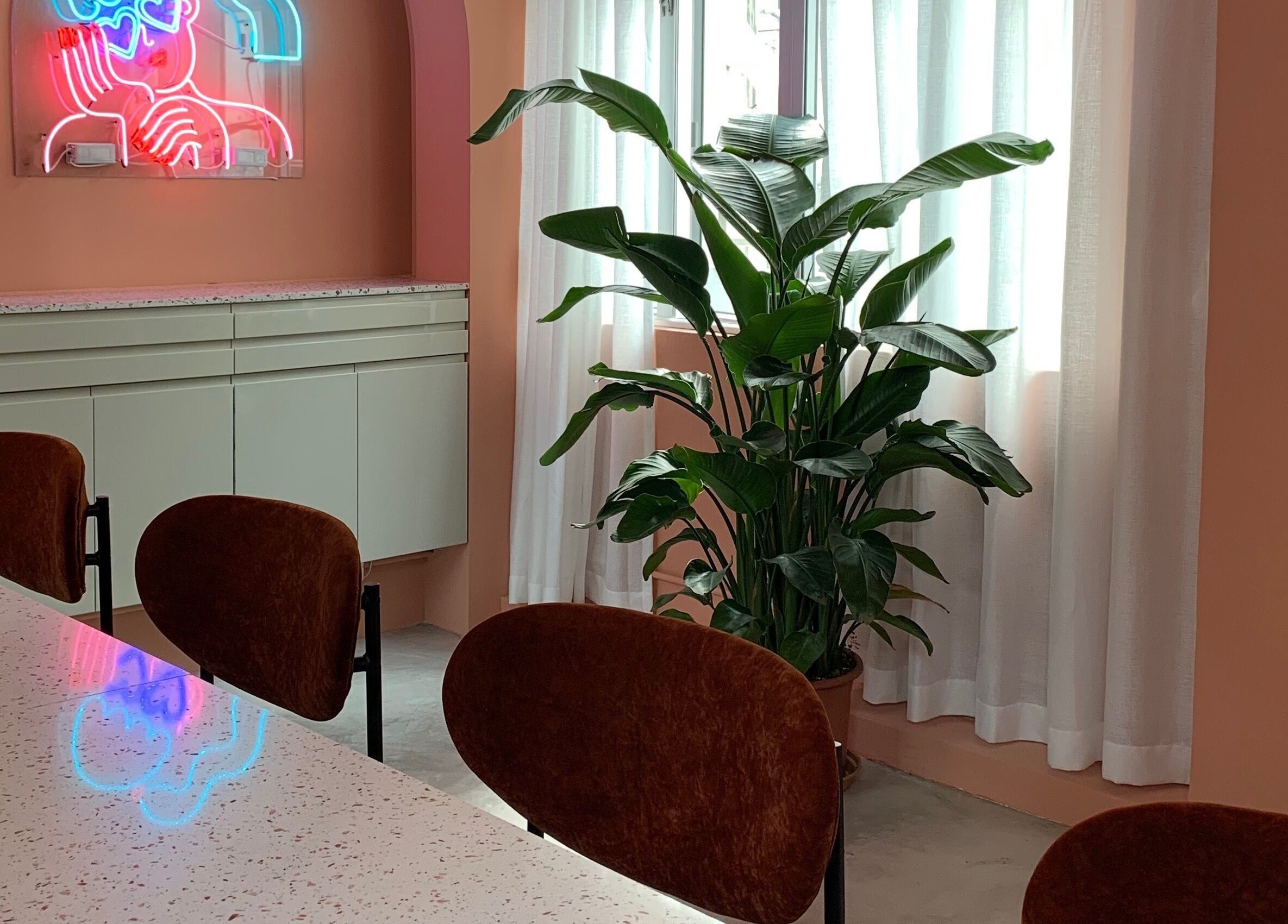 Chic interior of Tinted. - Causeway Bay on Hong Kong Island with neon art and lush plant.